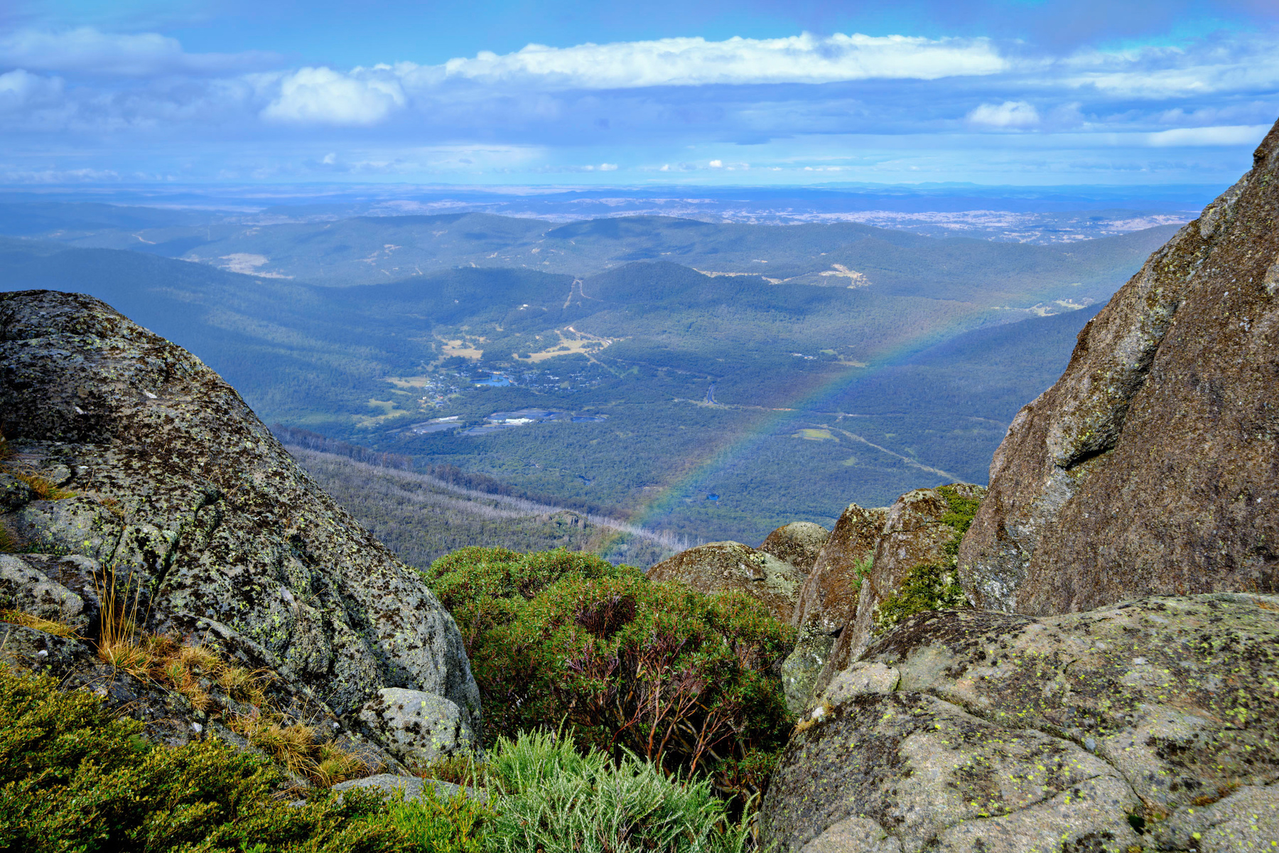 A rainbow over Porcupine Rocks, with a view over the Thredbo River valley below.